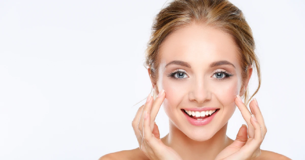 A smiling woman with glowing, healthy skin touching her result of professional skincare treatments in Cornelius, NC